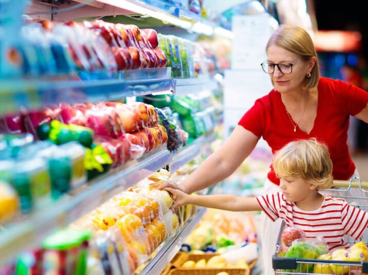Shopping with kids. Mother and child buying fruit in supermarket. Mom and little boy buy fresh mango in grocery store. Family in shop. Parent and children in a mall choosing vegetables. Healthy food.
