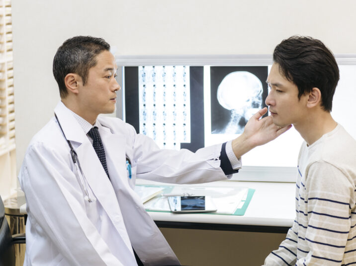 Doctor examining patient's jaw in hospital