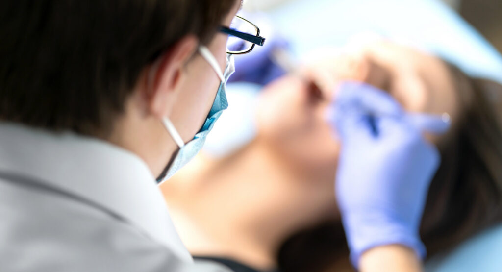 Dentist or dental hygienist in operation with patient. Woman with calculus or caries. Oral doctor removing wisdom teeth. Dentistry. Specialist operating.