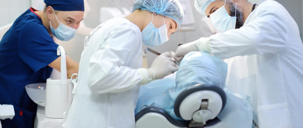 Surgeon and nurse during a dental operation. Anesthetized patient in the operating room. Installation of dental implants in the clinic.