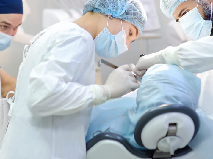 Surgeon and nurse during a dental operation. Anesthetized patient in the operating room. Installation of dental implants in the clinic.