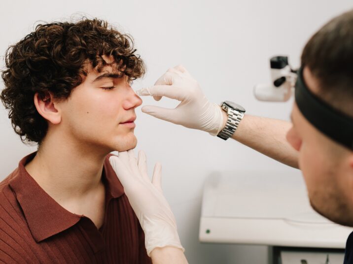 Rhinoplasty surgery preparation for man. ENT is touching nose consulting man. Final examination before septoplasty surgery.
