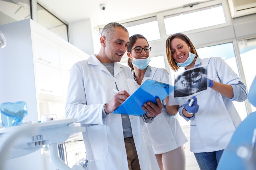 Group,Of,Dentists,Examining,X-ray,Image,Of,Patients,Teeth.,Standing
