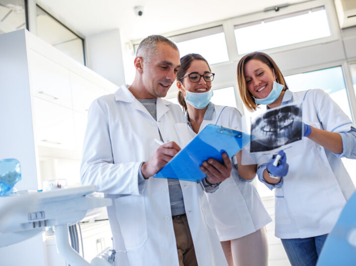 Group,Of,Dentists,Examining,X-ray,Image,Of,Patients,Teeth.,Standing