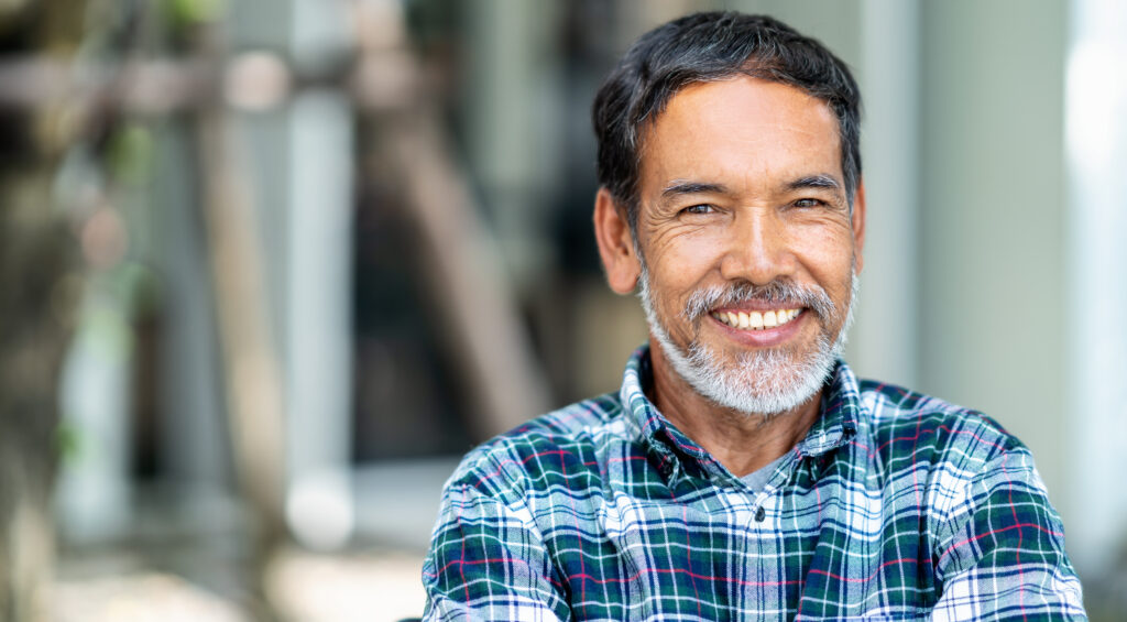 Portrait of happy mature man with white, grey stylish short beard looking at camera outdoor. Casual lifestyle of retired hispanic people or adult asian man smile with confident at coffee shop cafe.