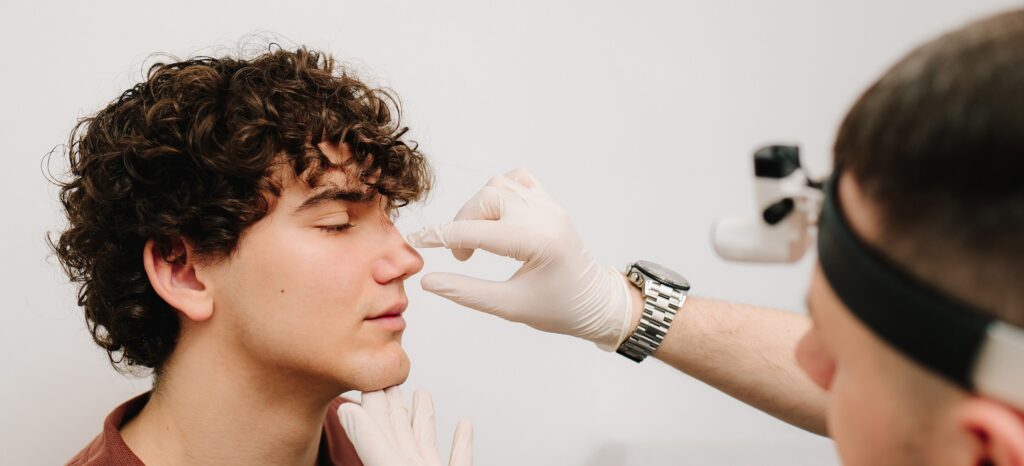 Rhinoplasty surgery preparation for man. ENT is touching nose consulting man. Final examination before septoplasty surgery.