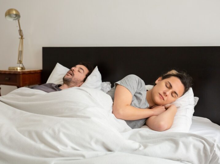 A couple soundly asleep in a cozy bedroom with classic decor, showcasing everyday serenity.